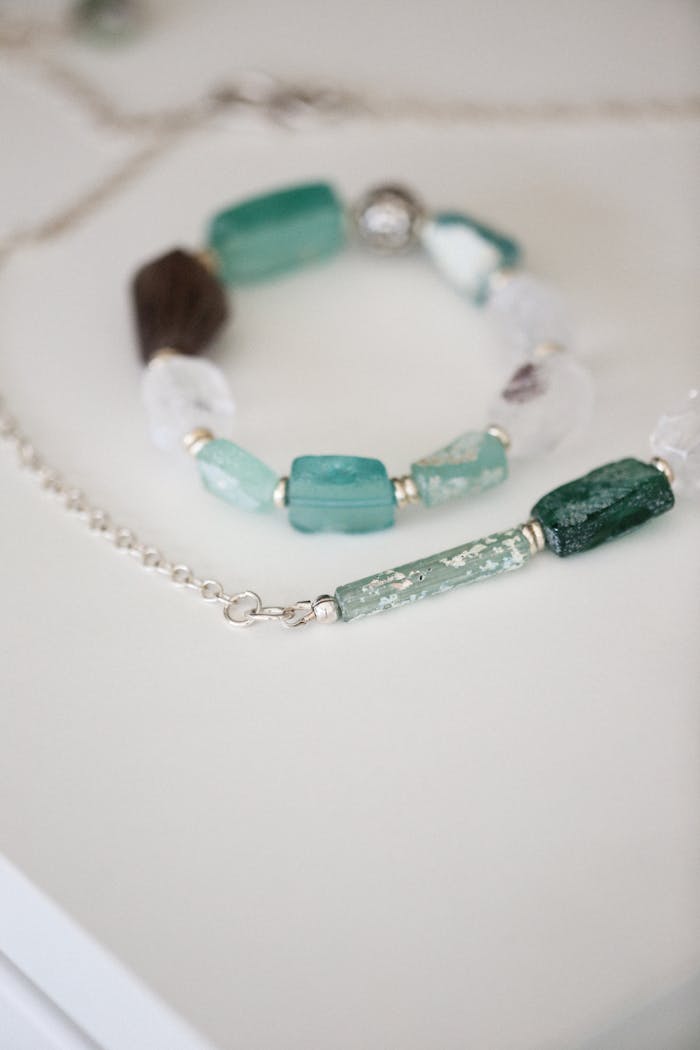 Crafting Captivating Headlines: Your awesome post title goes here Close-up of a stylish teal crystal necklace with silver chain on a smooth white surface.